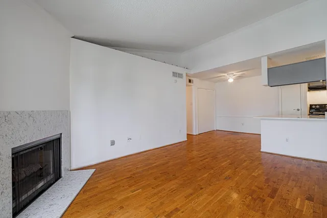 a view of empty room with wooden floor and fireplace