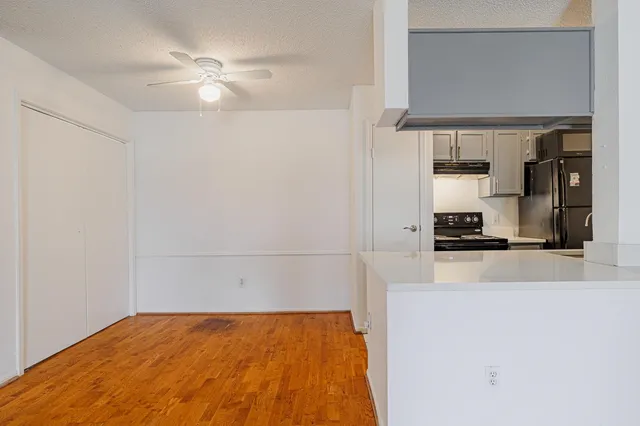 a view of kitchen and empty room with wooden floor