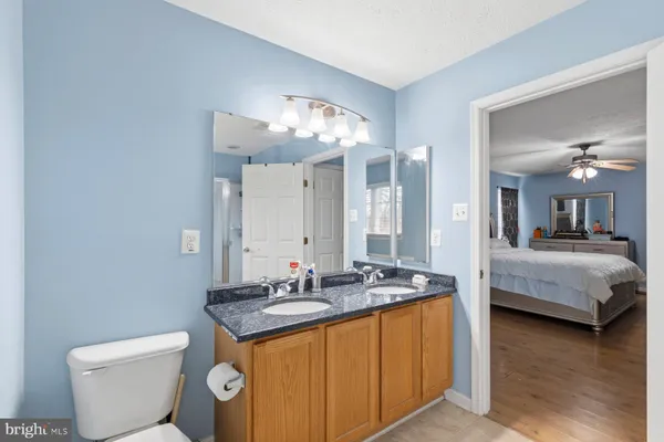 a bathroom with a granite countertop sink a toilet and a mirror