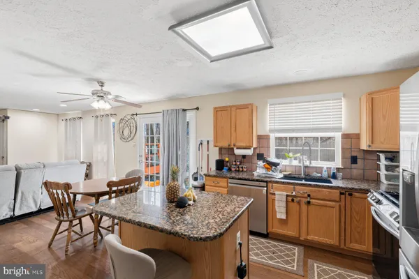 a kitchen with stainless steel appliances granite countertop a table chairs sink and window