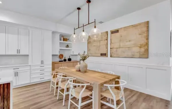 a kitchen with stainless steel appliances a dining table chairs and wooden floor