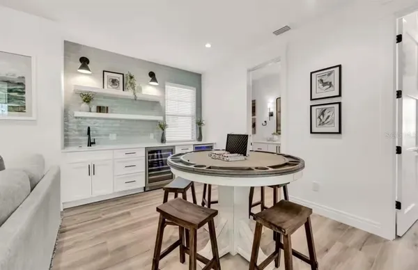 a kitchen with stainless steel appliances kitchen island a table chairs in it and white cabinets