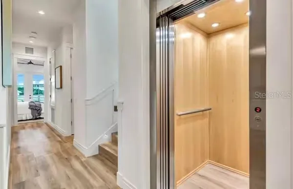 a view of a hallway with wooden floor and a bathroom