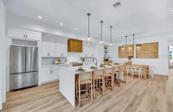 a kitchen with stainless steel appliances granite countertop a dining table chairs stove refrigerator and cabinets