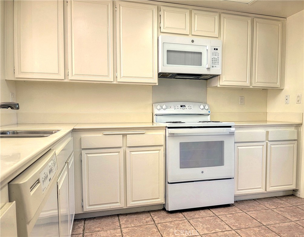 3370 Punta Alta, Unit C Laguna Woods, CA 92637 - Photo 11 of 29 a kitchen with white cabinets and white appliances