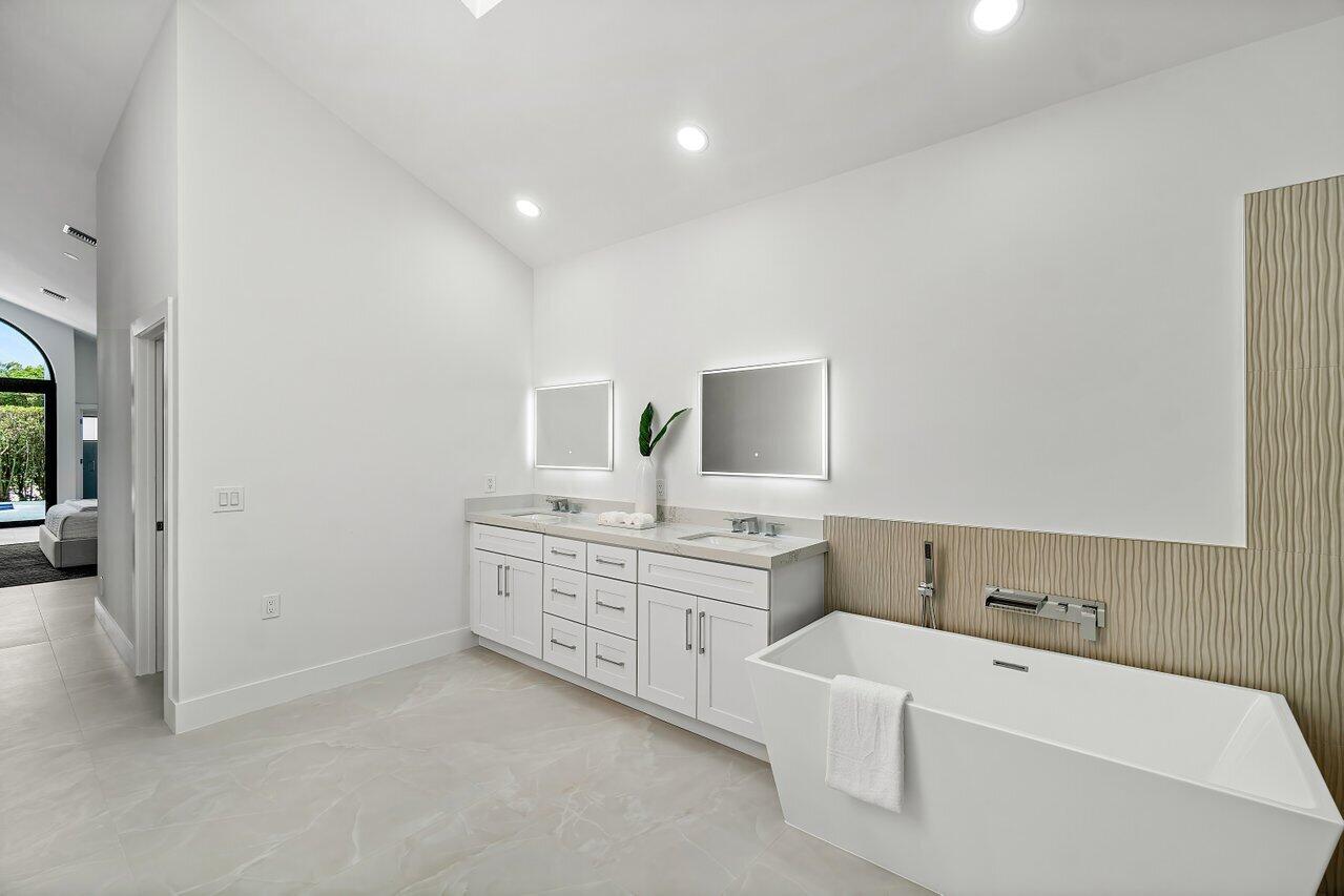 5529 Steeple Chase Boca Raton, FL 33496 - Photo 19 of 56 a spacious bathroom with a granite countertop sink a mirror and bathtub