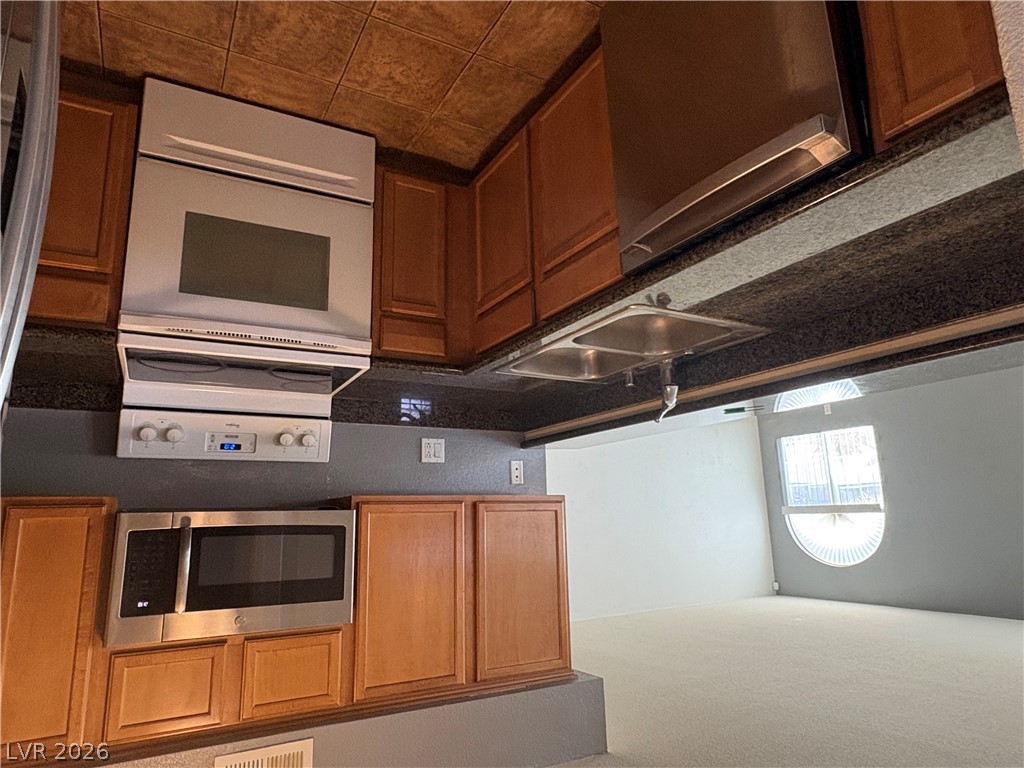 9325 West Desert Inn Road, Unit 123 Las Vegas, NV 89117 - Photo 19 of 36 A functional kitchen boasts ample cabinetry, a double sink, and modern appliances.