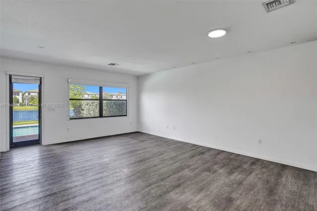 a view of an empty room with window and wooden floor
