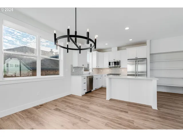 a open kitchen with white cabinets and wooden floor