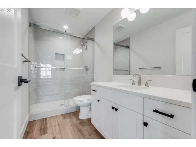 a bathroom with a sink a toilet a mirror and shower