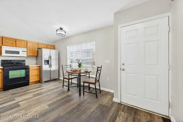 a view of an empty room with a window and kitchen view