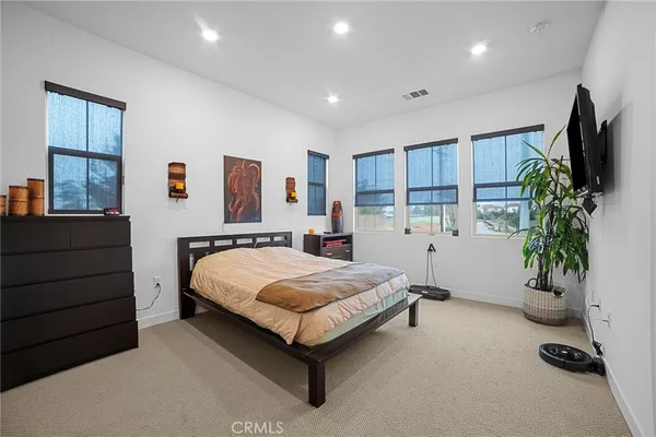 a spacious bedroom with a bed and a flat screen television