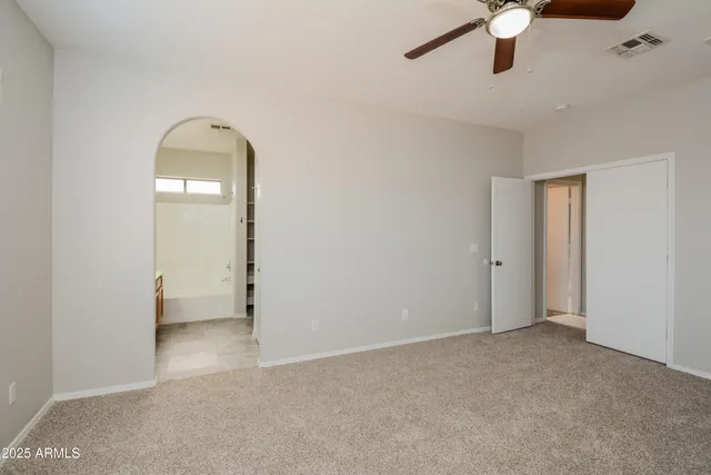 an empty room with a ceiling fan and wooden floor