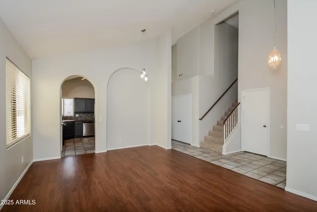 a view of empty room with wooden floor and kitchen