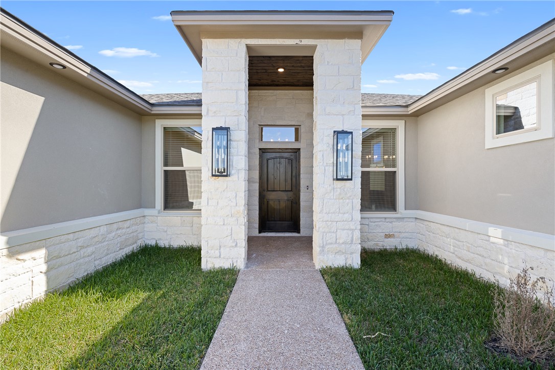 6512 Agave Court Bryan, TX 77808 - Photo 4 of 42 View of exterior entry with stone siding, a lawn, and stucco siding
