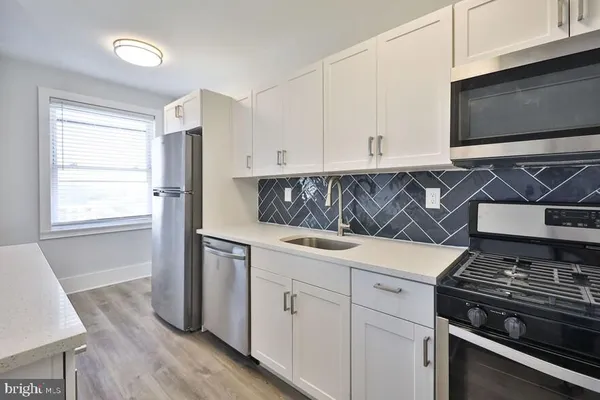 a kitchen with stainless steel appliances white cabinets and a stove top oven