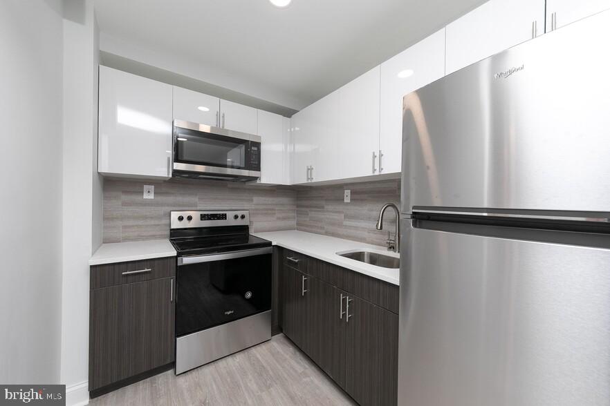 4247 Locust Street, Unit 1B714 Philadelphia, PA 19104 - Photo 21 of 38 a kitchen with stainless steel appliances granite countertop a sink stove and microwave