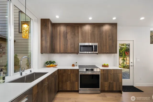 a kitchen with stainless steel appliances granite countertop a refrigerator a sink a stove a microwave and wooden cabinets