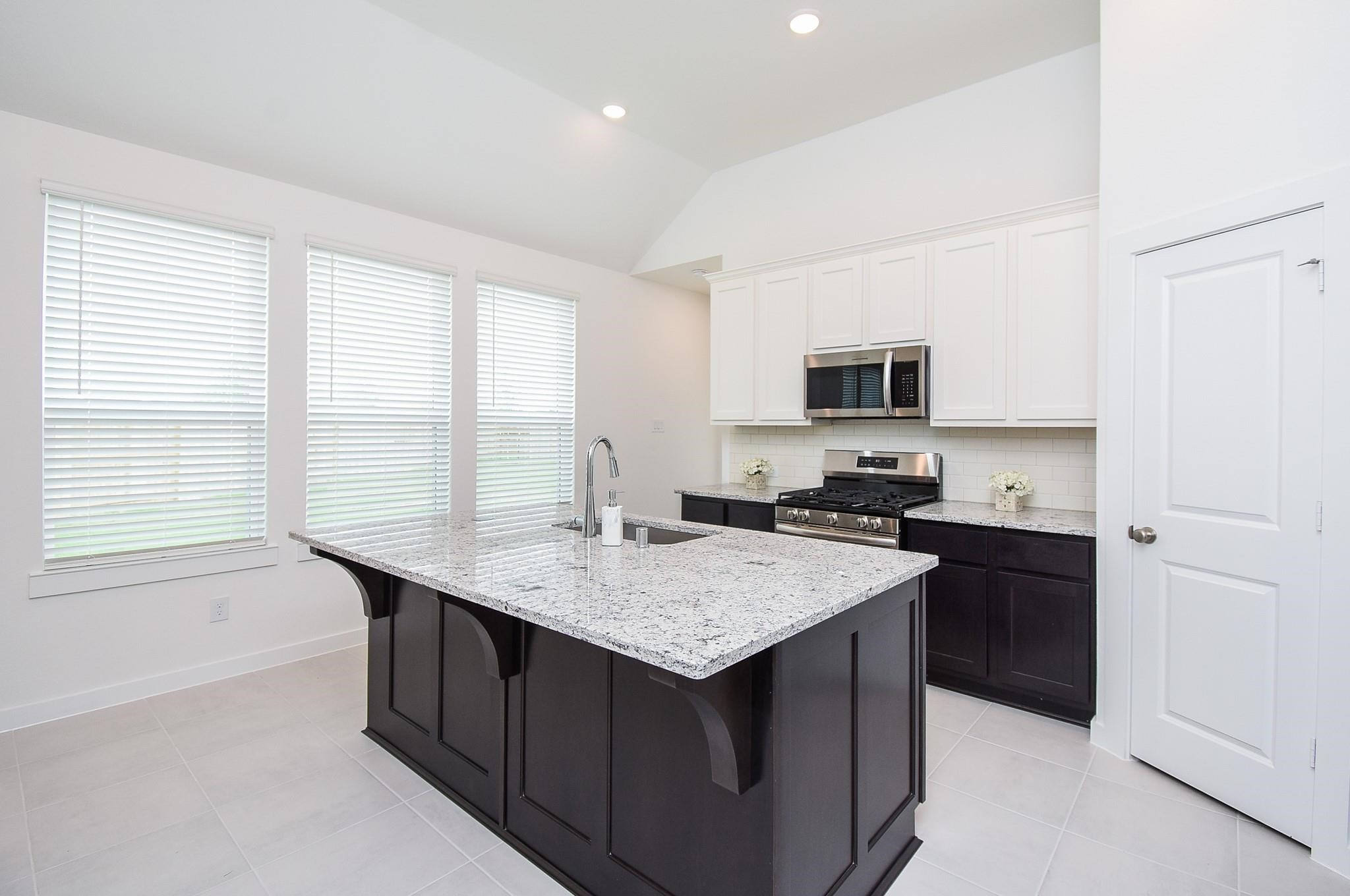 5115 Murillo Drive Manvel, TX 77578 - Photo 10 of 31 a kitchen with a stove a sink a microwave and cabinets