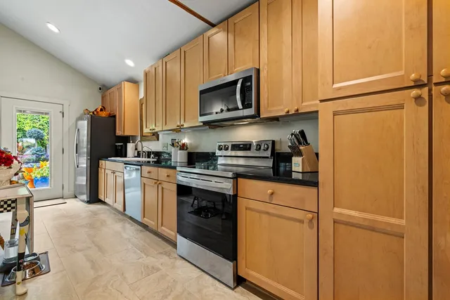 a kitchen with stainless steel appliances granite countertop a refrigerator stove a sink dishwasher and microwave with wooden floor