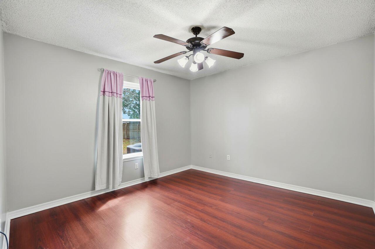 1285 Jefferyscot Drive Crestview, FL 32536 - Photo 22 of 41 an empty room with wooden floor chandelier fan and windows
