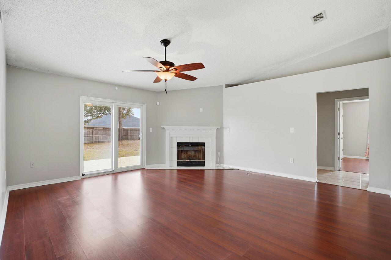 1285 Jefferyscot Drive Crestview, FL 32536 - Photo 10 of 41 a view of an empty room with wooden floor fireplace and a window