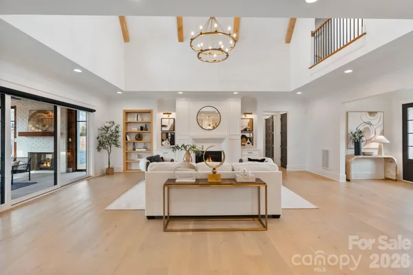 a living room with furniture a fireplace kitchen view and a flat screen tv