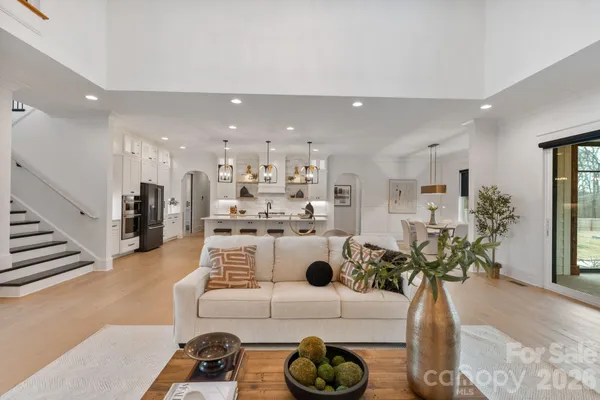 a living room with couches a coffee table and kitchen view with wooden floor