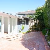 a view of a house with potted plants and a large tree