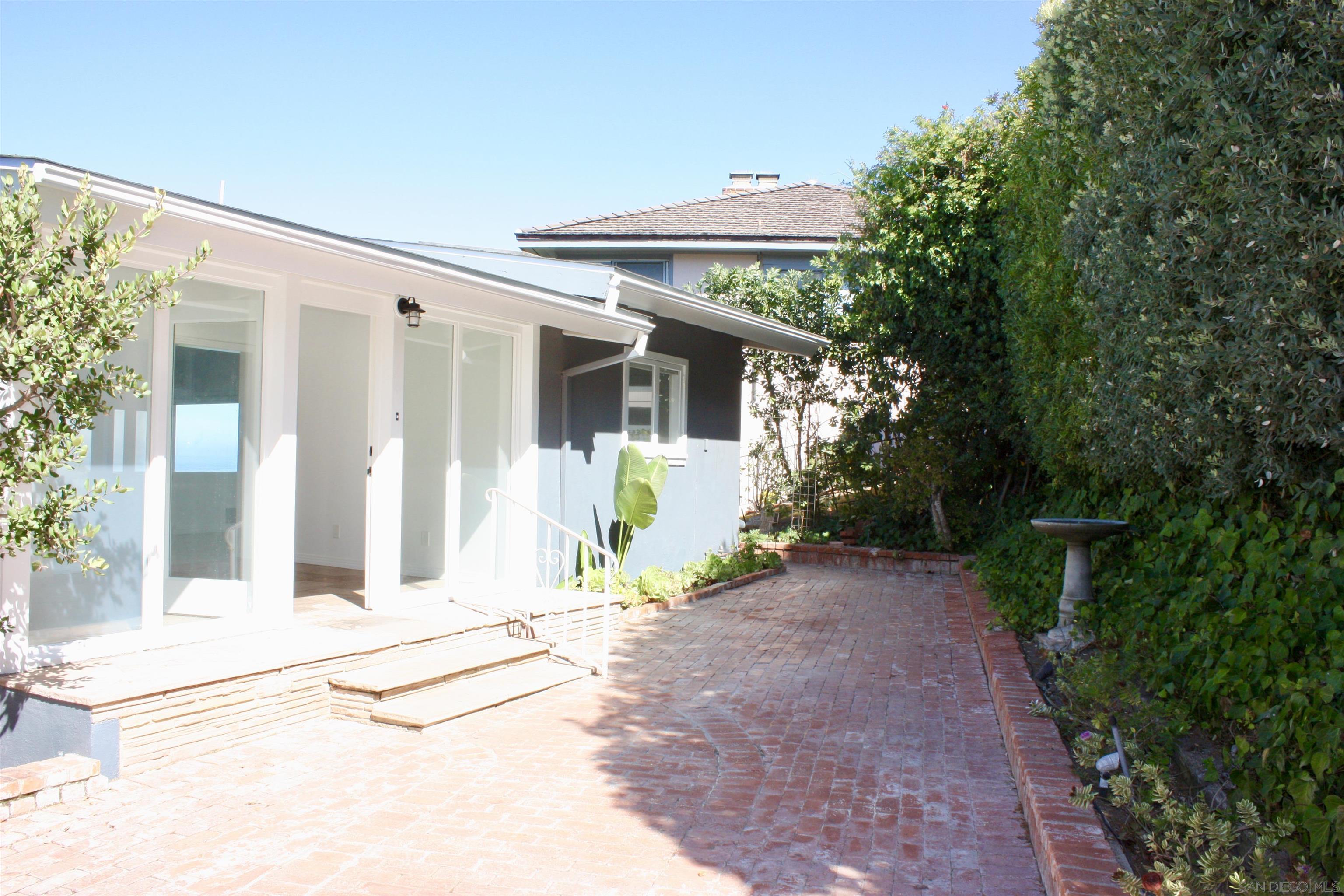 a view of a house with potted plants and a large tree
