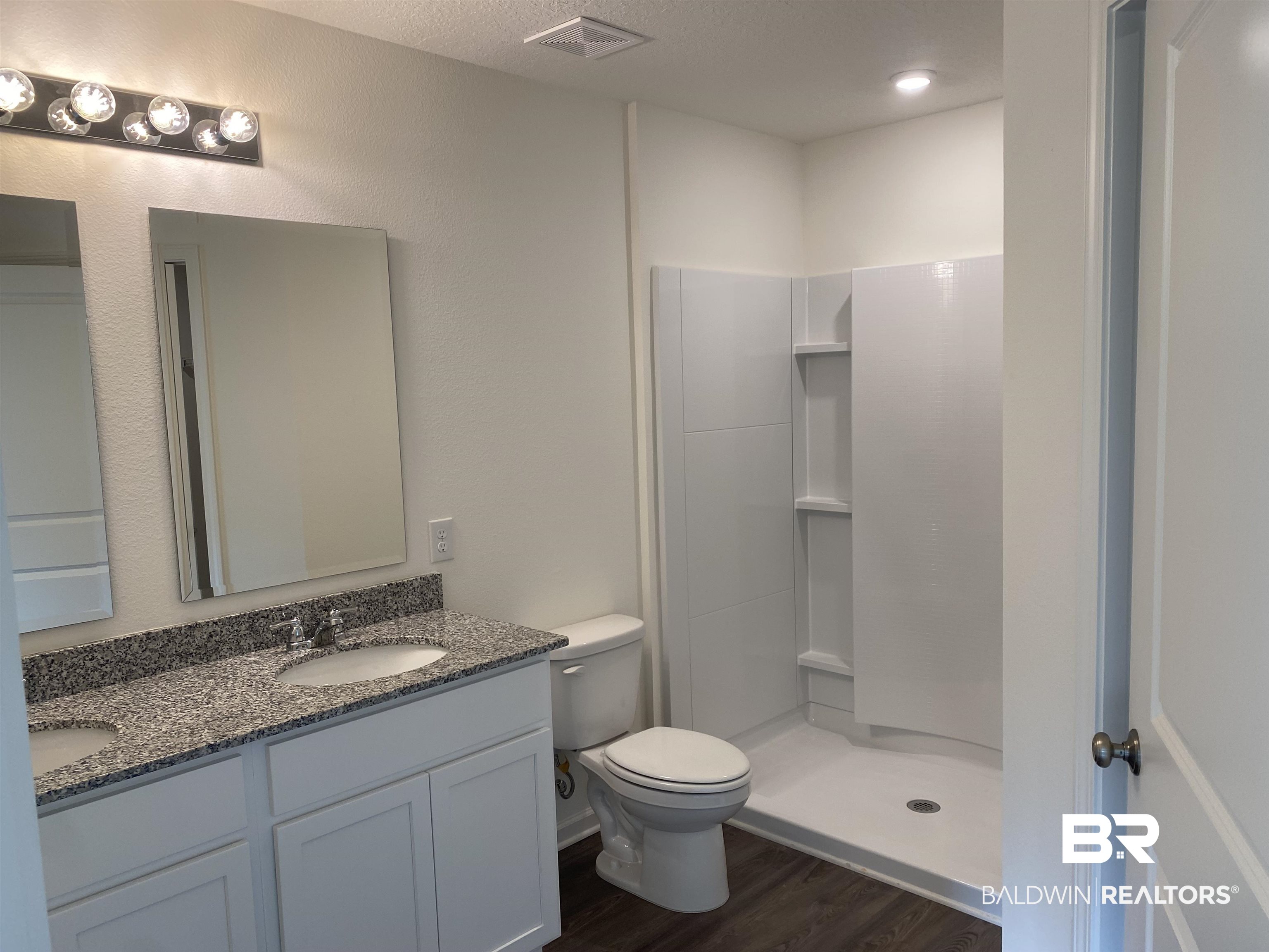 21641 Sutherland Circle Fairhope, AL 36532 - Photo 11 of 17 Bathroom with a textured ceiling, vanity, wood-type flooring, walk in shower, and toilet