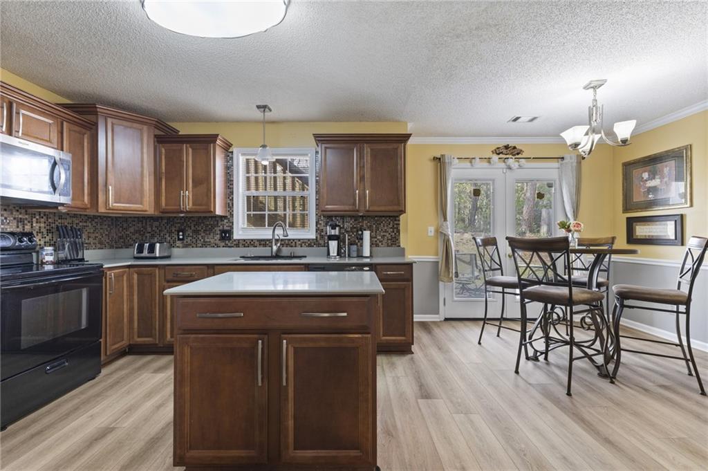 4008 Lindsey Lane Rex, GA 30273 - Photo 14 of 34 a kitchen with stainless steel appliances granite countertop a stove a sink dishwasher a microwave oven and a dining table with wooden floor