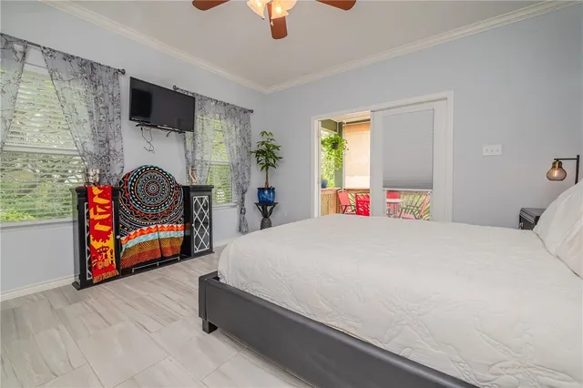 a bedroom with a bed a chandelier and a flat tv screen on dresser