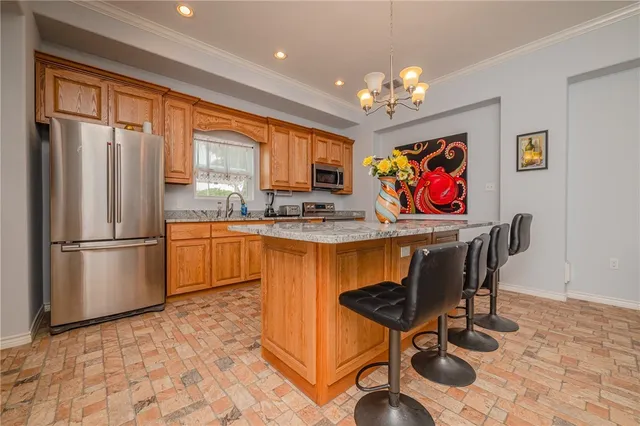 a kitchen with stainless steel appliances granite countertop a refrigerator a sink dishwasher a dining table and chairs with wooden floor