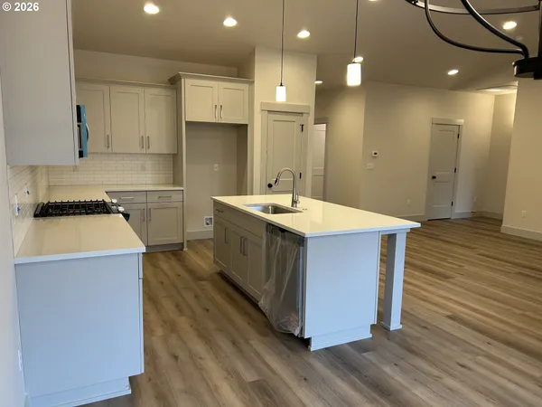 a kitchen with a sink a stove cabinets and wooden floor