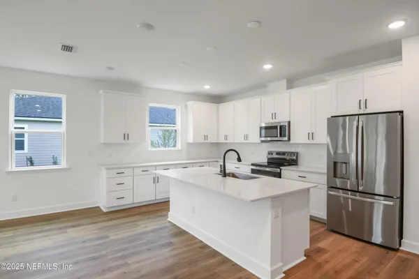 a kitchen with a refrigerator sink and cabinets