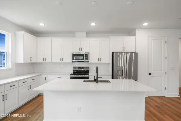 a kitchen with stainless steel appliances a refrigerator sink and white cabinets