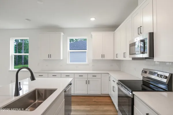a kitchen with granite countertop a stove a sink and a microwave