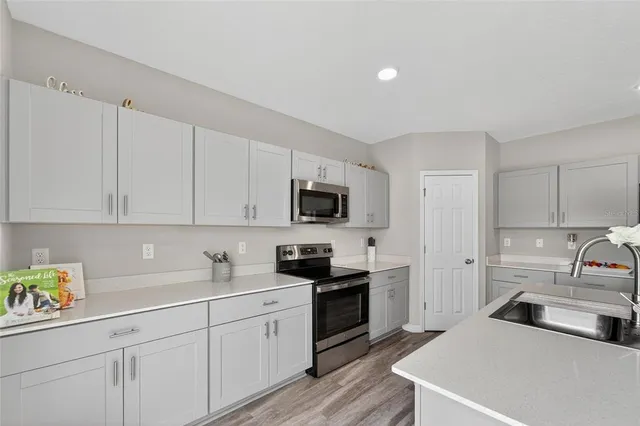 a kitchen with stainless steel appliances granite countertop white cabinets and a stove a oven with white countertops