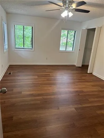 an empty room with wooden floor and windows