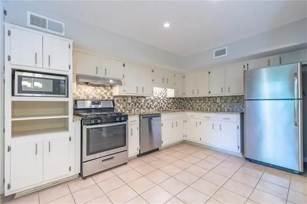 a kitchen with granite countertop white cabinets and stainless steel appliances