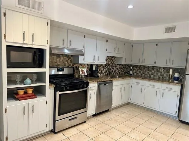 a kitchen with stainless steel appliances granite countertop a stove a sink and a microwave