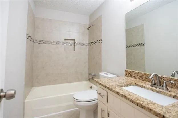 a bathroom with a granite countertop sink a toilet and shower