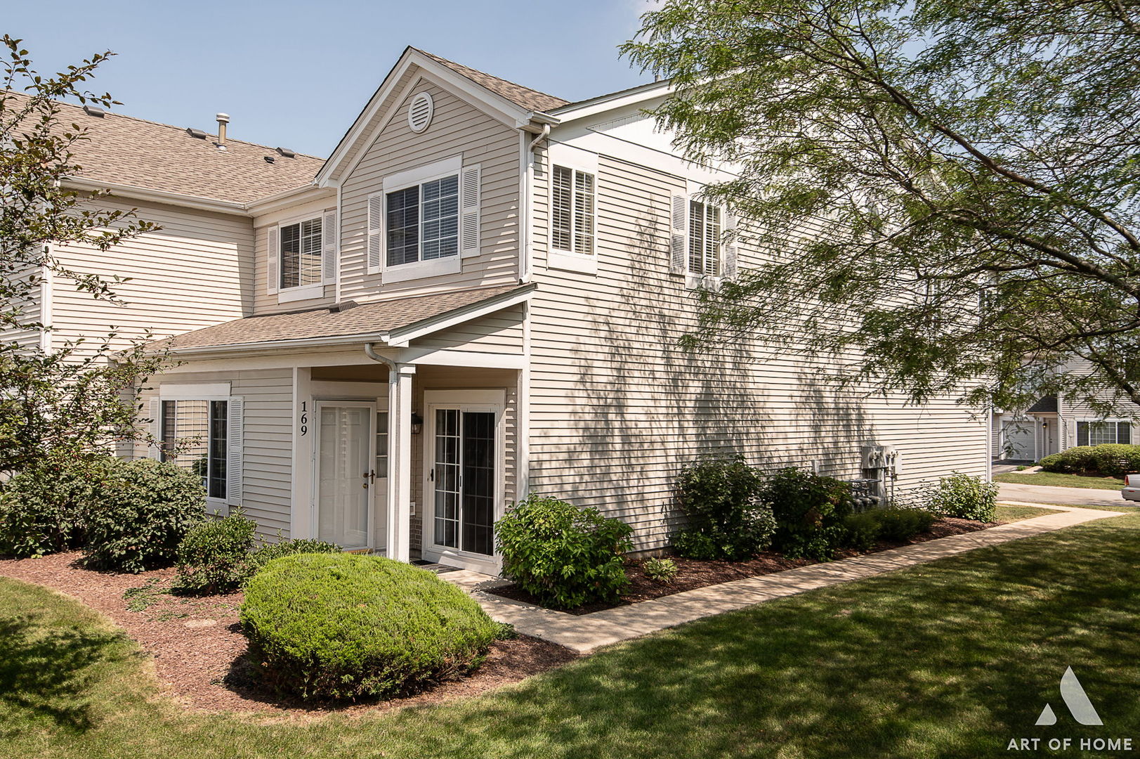 a view of a white house next to a yard and a large tree