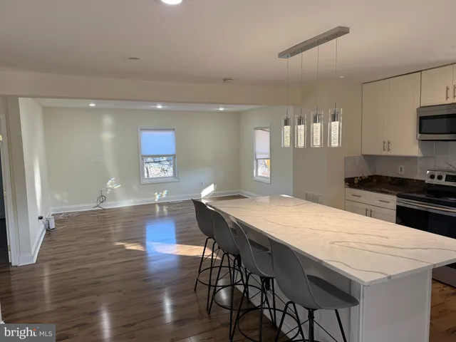 a kitchen with stainless steel appliances kitchen island granite countertop a stove a table and chairs in it