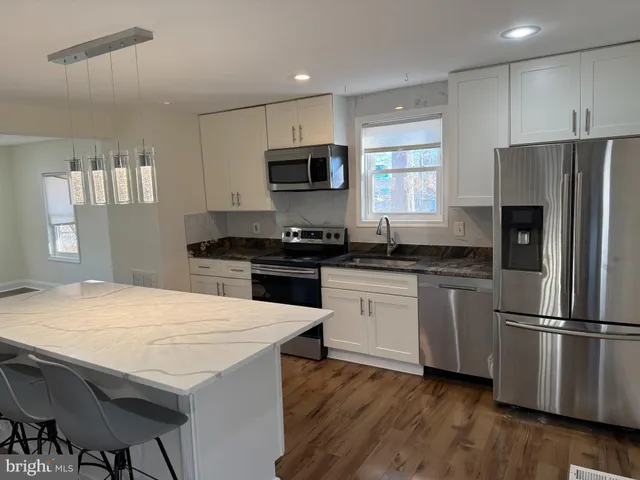 a kitchen with granite countertop a refrigerator stove top oven and sink