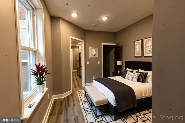 a bedroom with a bed and a large mirror next to a window