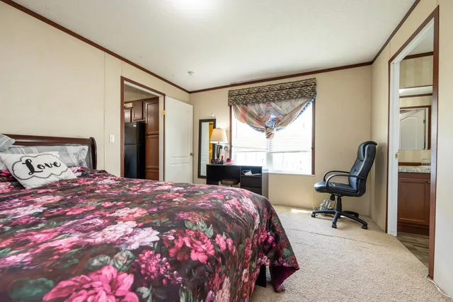 a bedroom with a bed large window and chair