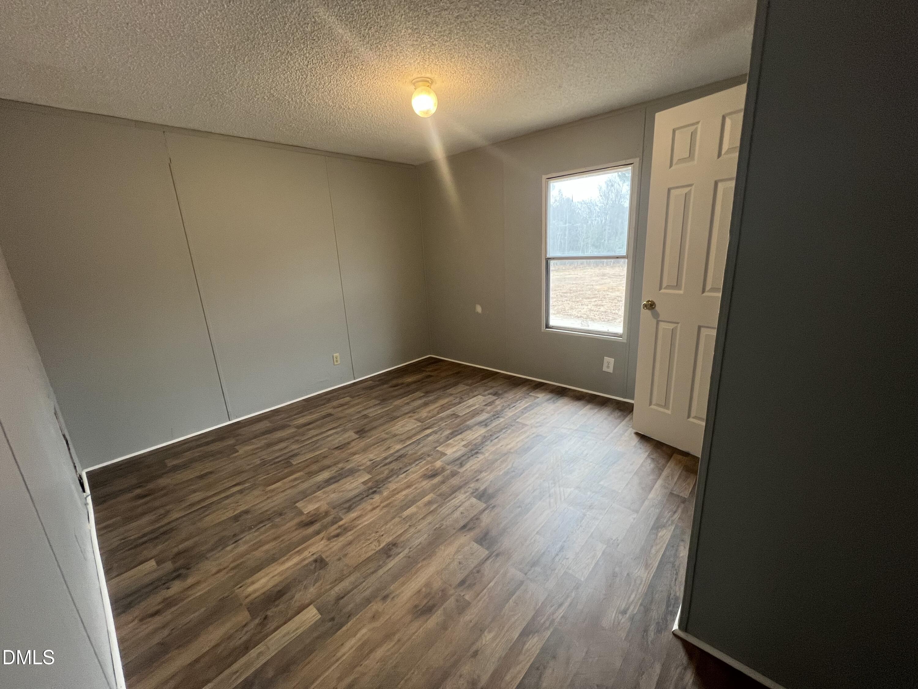 172 Pine Forest Loop Louisburg, NC 27549 - Photo 7 of 9 an empty room with wooden floor and windows