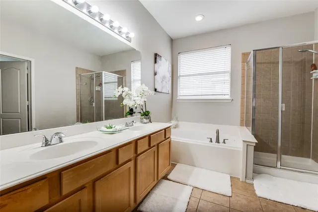 a spacious bathroom with a bathtub double sink and mirror